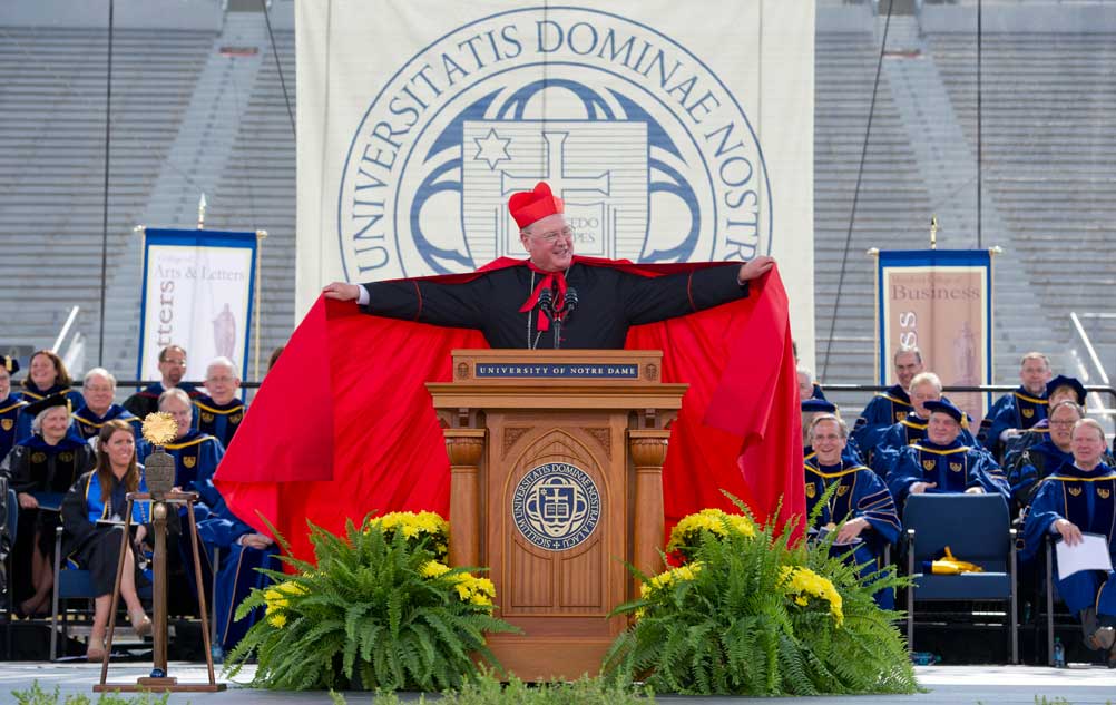 May 19, 2013; Timothy Cardinal Dolan, Archbishop of New York and Commencement speaker, jokes with the audience as he lifts his cape at the 2013 Commencement ceremony in Notre Dame Stadium. Photo by Barbara Johnston/University of Notre Dame