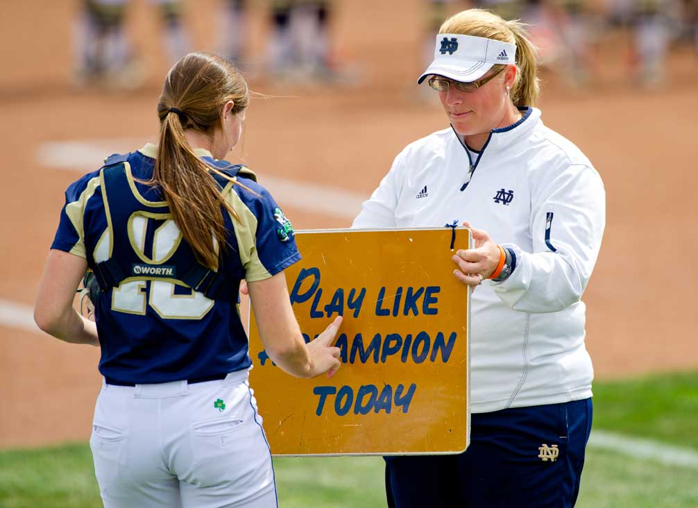 May 4, 2013; Associate Softball coach Kris Ganeff holds the 'Play Like A Champion Today' sign for catcher Amy Buntin before a game...Photo by Matt Cashore/Univeristy of Notre Dame
