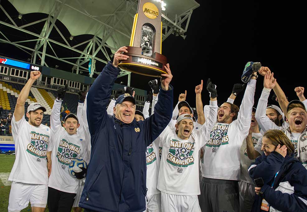 Dec 15, 2013; Notre Dame head coach Bobby Clark holds up the College Cup championship trophy as he celebrates with his team after they defeated Maryland 2-1. Photo by Barbara Johnston/University of Notre Dame