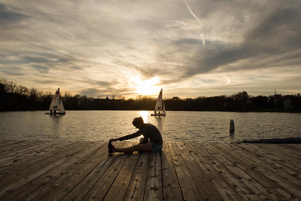 Nov. 5, 2014; Enjoying the unseasonably warm temperatures, sophomore psychology and pre-med student, Patty Morrow stretches after her afternoon jog around St. Joseph Lake. (Photo by Barbara Johnston/University of Notre Dame)